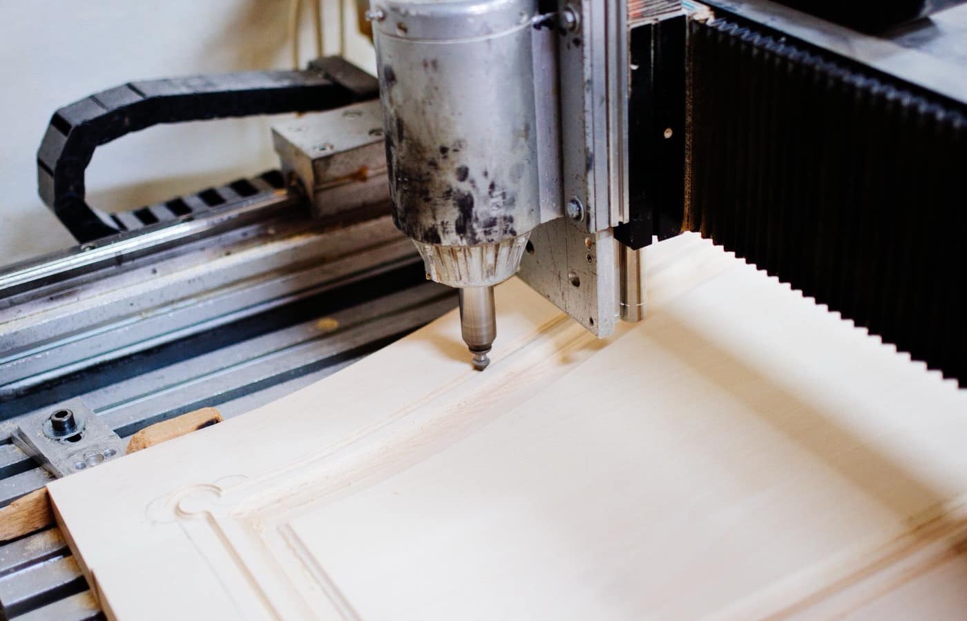 The head of a computer-controlled milling machine cutting a part on its bed.