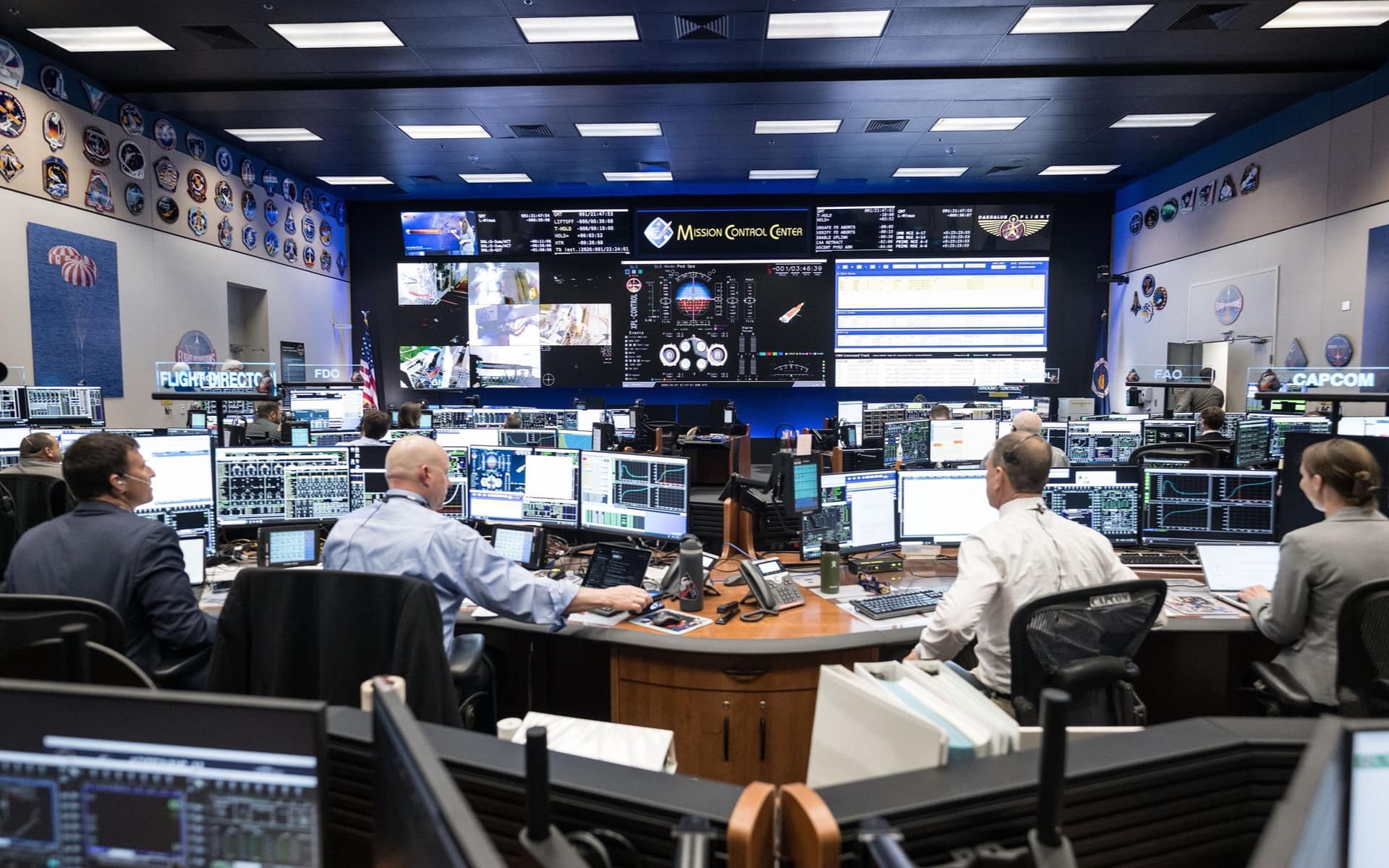 An operations room: staff at consoles facing a wall of screens, each watching a different feed.