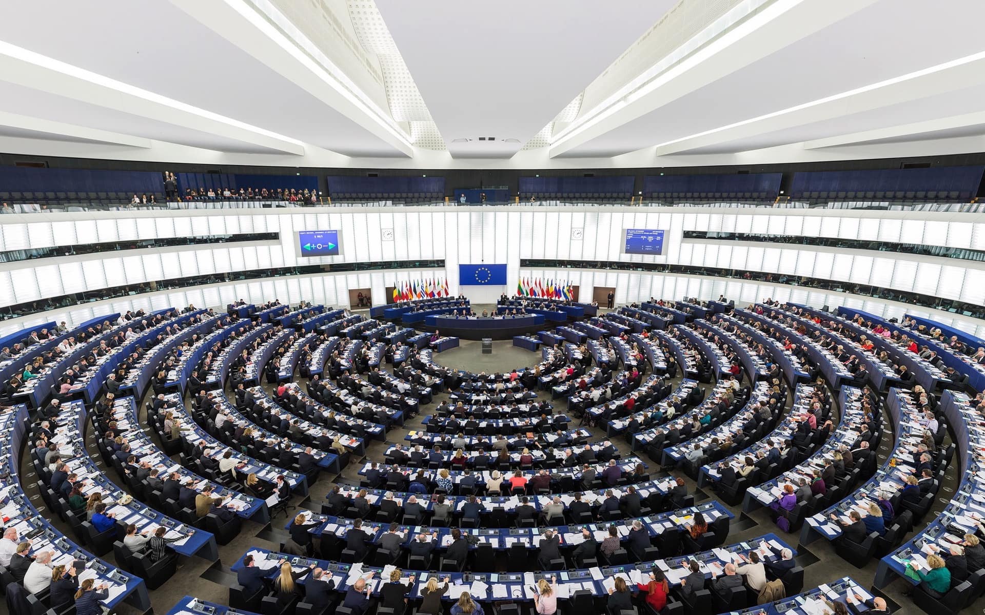 The European Parliament chamber in Strasbourg, seats curving in tiers around the rostrum.