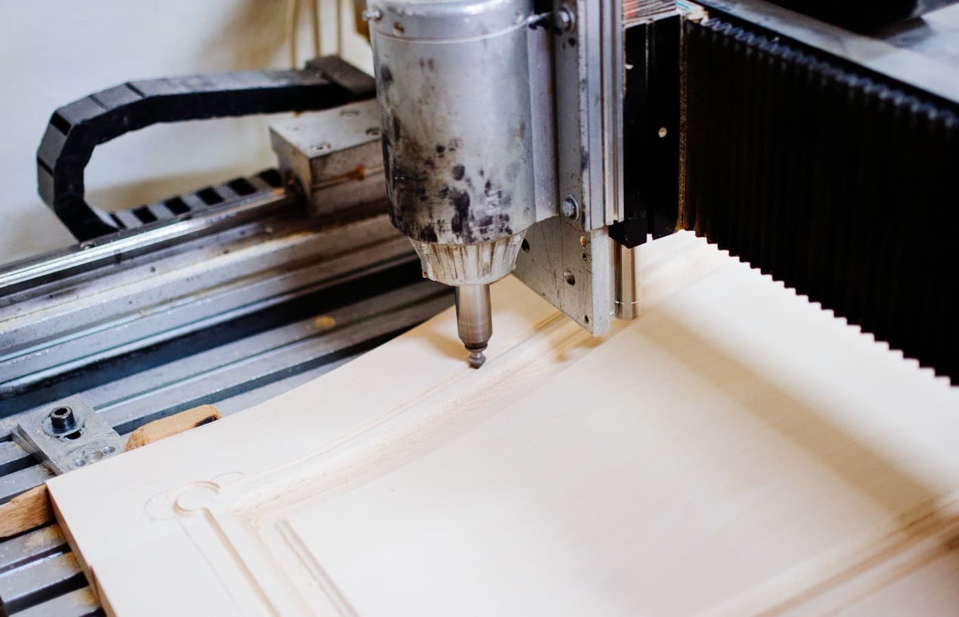 The head of a computer-controlled milling machine cutting a part on its bed.