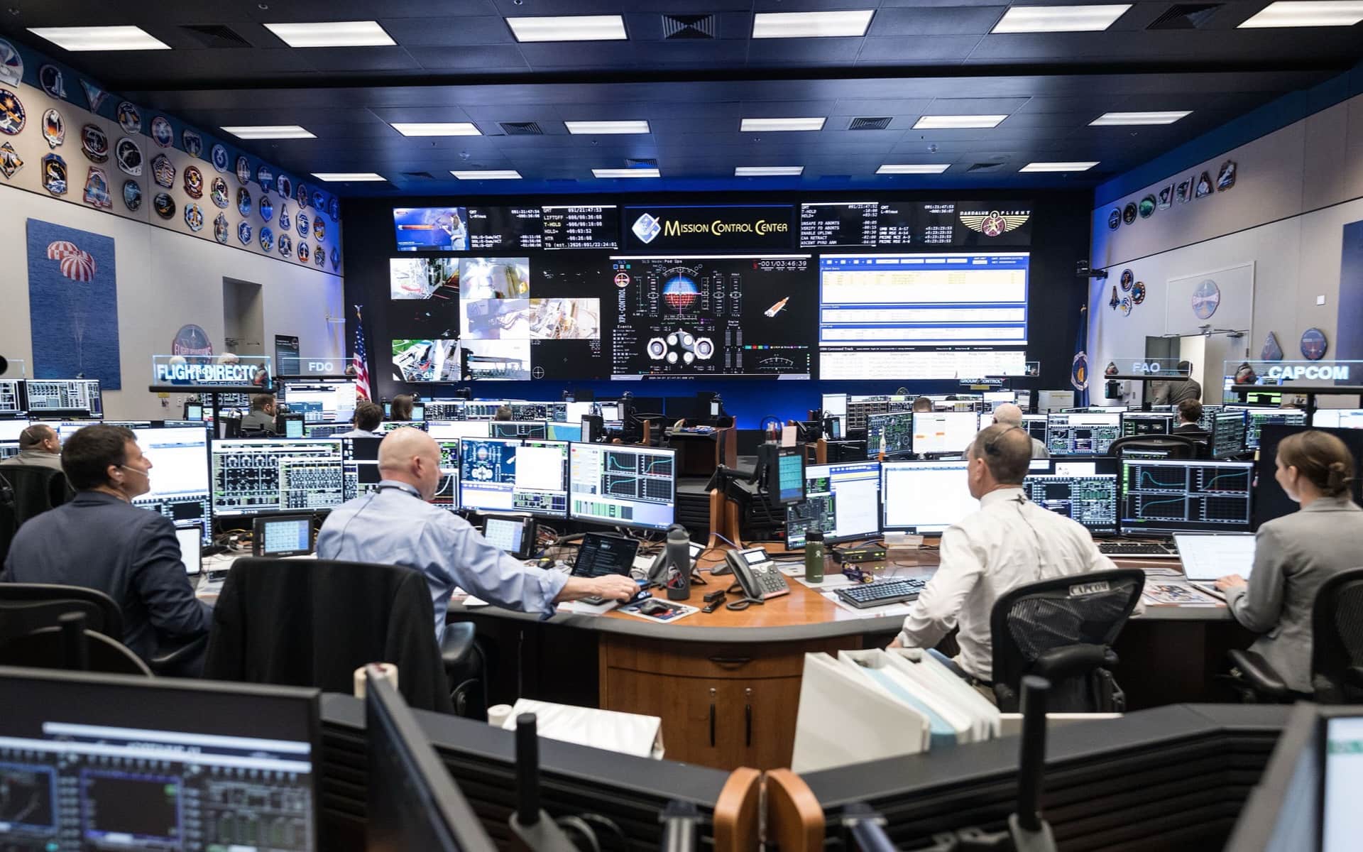 An operations room: staff at consoles facing a wall of screens, each watching a different feed.