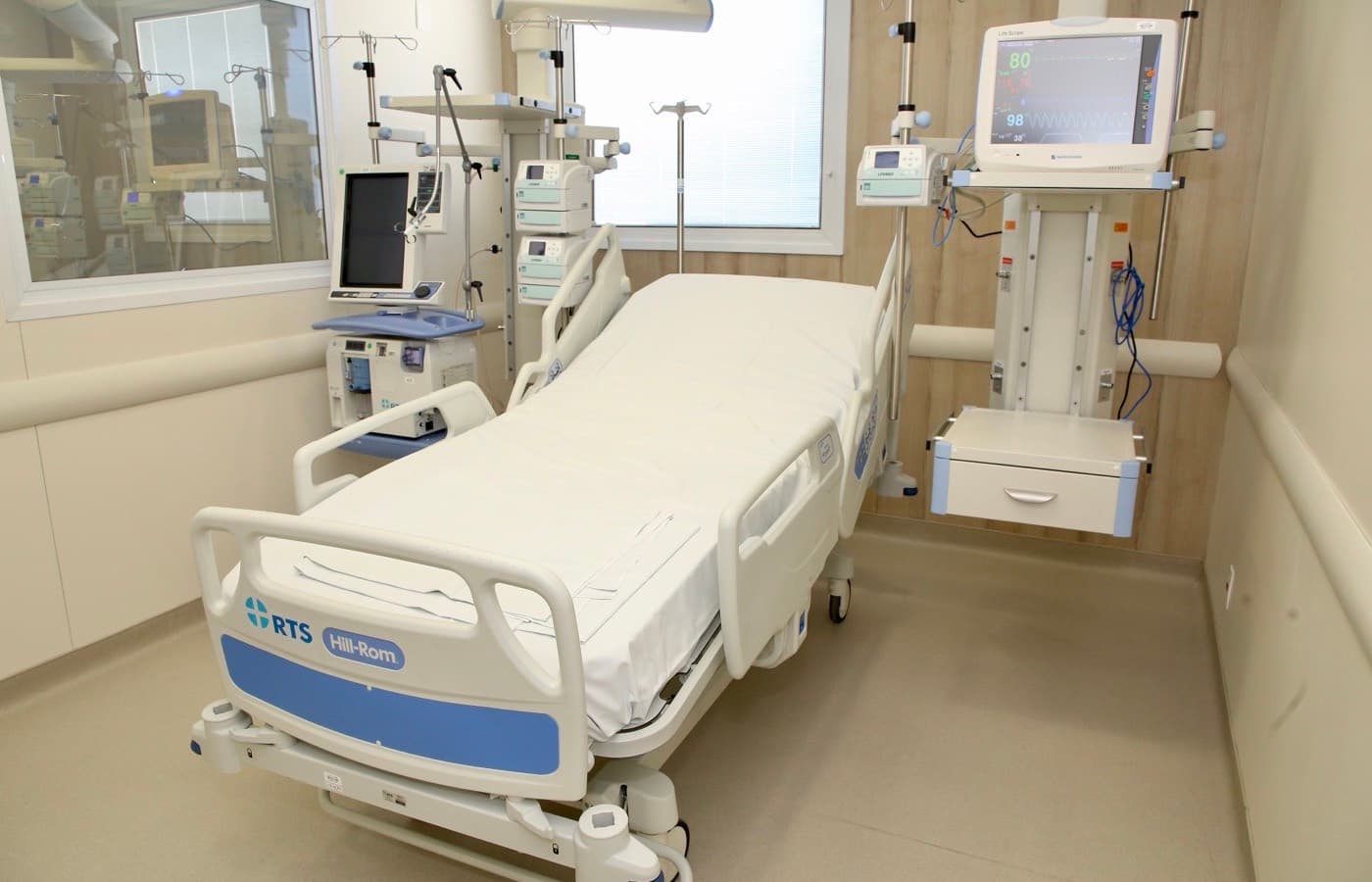 An empty intensive care room, the bed flanked by monitoring and ventilation equipment.