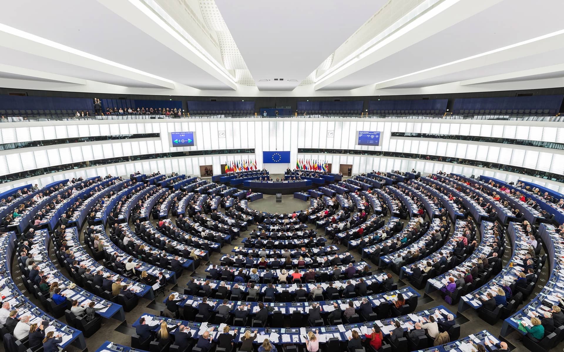 The European Parliament chamber in Strasbourg, seats curving in tiers around the rostrum.
