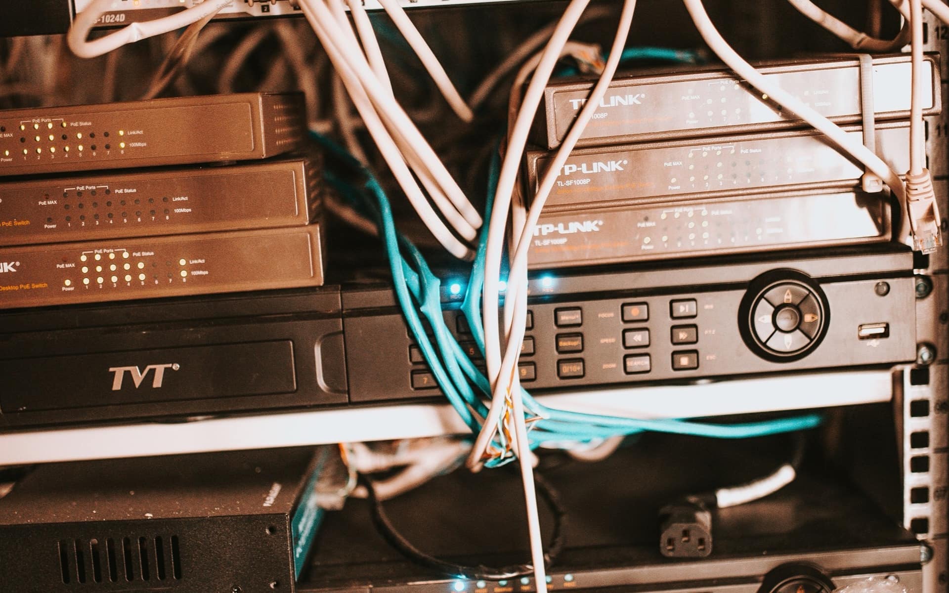Switches and routers stacked in a rack, patch cables running between their ports.